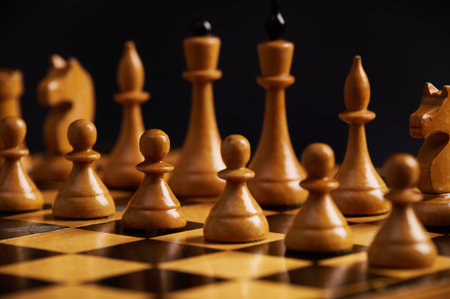 White chess pieces standing in start positions on the chessboard, over isolated black background....