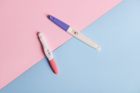 Top view inkjet pregnancy tests with taking place biochemical reaction between female urine and chorionic human gonadotropin hormone, appearing in two bars, on blue pink background. Finally pregnantの写真素材