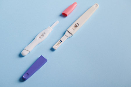 Top view inkjet pregnancy tests with taking place biochemical reaction between female urine and chg hormone, appearing in two bars, showing positive result over blue background. Finally pregnantの写真素材