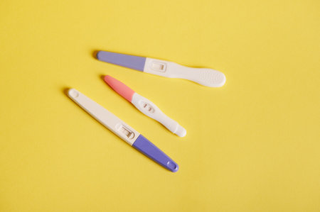 Still life. Flat lay of three kits of pregnancy tests with positive result, isolated on yellow background. Planning pregnancy and maternity concept. Copy ad space.の写真素材