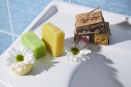Still life with various handmade eco soap bars and solid shampoo with natural ingredients of lavender, coffee beans, olive oil, essential oils and chamomile, on a white ceramic surface in the bathroomの写真素材