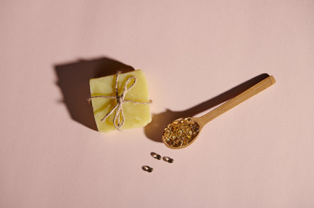 View from above of transparent gelatin capsules in a wooden spoon, and soap bar with natural organic ingredients, tied with linen rope on isolated pink pastel background. Hygiene and body care conceptの写真素材