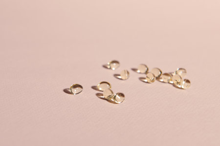 Omega 3 or vitamin D gel capsules scattered on pink pastel background with copy advertising space....