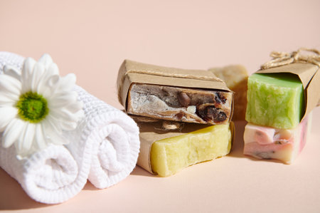 Still life with spa set: white rolled towels and organic homemade cold-pressed soap bars with...