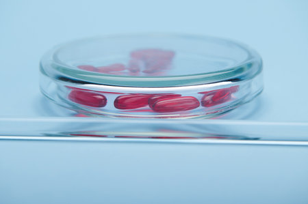 Selective focus on red soft gelatin translucent capsules with fat-soluble vitamins or omega inside a...