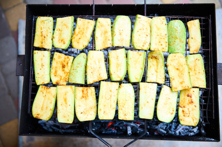 Top view raw marinated seasoned slices of zucchini, grilled on barbecue, vegetarian vegan summer food. Preparing delicious food in the open air. Summer picnic and chill out concept. Close-up BBQの写真素材