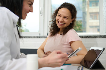 Doctor gynecologist discusses with pregnant woman about the ultrasound scan of baby, examines gravid patient and prescribes nutritional supplement for healthy pregnancy. Obstetrics and gynecologyの写真素材
