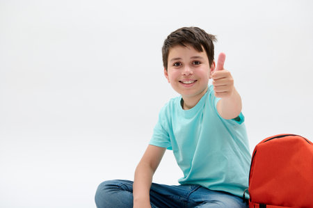 Happy cheerful smiling child, teenager with orange backpack, smart schoolboy in blue casual denim,...