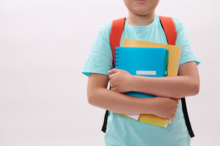 Close-up schoolboy's hands holding textbooks and workbook, isolated on white studio background. Copy advertising space. Back to school on new semester of academic year. Education. Learning. Smart kidsの写真素材