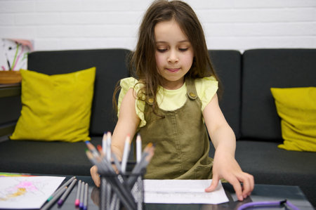 Caucasian beautiful child, adorable baby girl draws pictures indoors. people. Art. Talent. Creative hobby. Kids education and entertainment conceptの写真素材