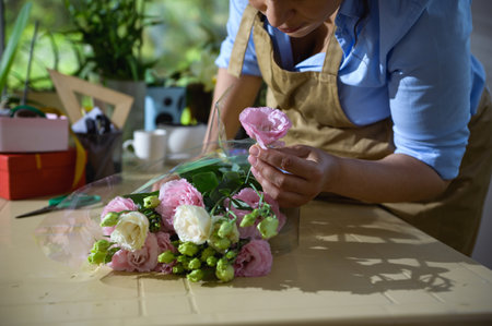 Close-up florist arranging a flower bouquet of fresh white and pink ranunculus, in floral design studio. Flower arrangements and gifts. Wedding Day. Happy Mother's Day and International Women's Dayの写真素材