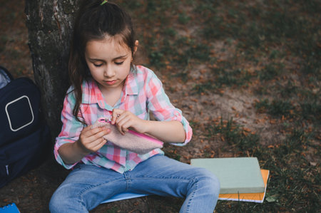 Caucasian cute little kid girl, smart primary school student opening her pencil case while doing...