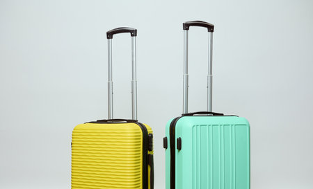 Two bright yellow and light green suitcases, isolated on white studio background with copy ad space. Luggage. Low cost. Air flight. Travel. Tourism. Trip. Weekend getaway. Summer vacations. Holidaysの写真素材