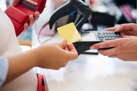 Close-up hands of a customer swiping a mockup golden credit card, making contactless payments. Paying goods using online internet banking, NFC technology. People. Business. Finance. Commerceの写真素材