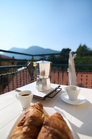 Still life with food. Selective focus on an Italian percolator, moka brewer on the table with served breakfast on the balcony in Italian village. Good morning and wonderful travel destinations conceptの写真素材