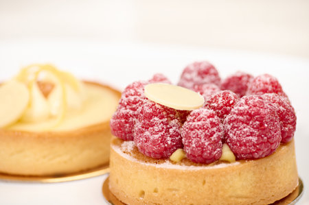 Close-up front view of cream tartlet decorated with fresh raspberries isolated on white background. Copy advertising spaceの写真素材