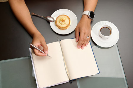 Close-up. View from above woman's hand using a stylish pen, taking notes on notebook, planning...