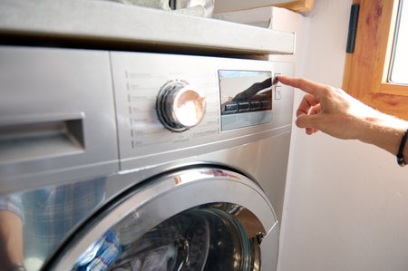 Close-up male hand switching on, turning on automatic washing machine or select program with knob on...