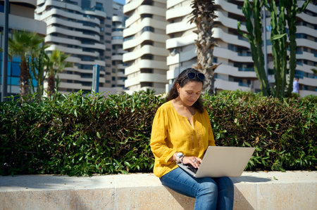 Multiethnic female entrepreneur, businesswoman, real estate agent dressed in casual clothes, working online outdoor. People. Freelance occupation. Remote job. Online businessの写真素材