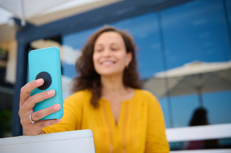 Details on hand of young adult pretty woman, successful blogger holding smart mobile phone, smiling...