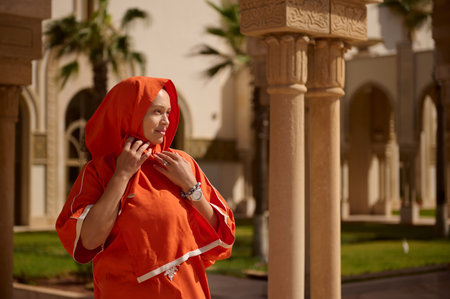 Beautiful young adult Middle Eastern Muslim woman with head covered in hijab, looking into the...