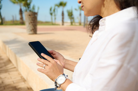 Close up of a business woman in white shirt, using smartphone and tapping screen while chatting online, copy space for mobile application. People. Technology. Internet Connection. Online communicationの写真素材