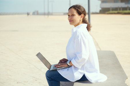 Multitasking thoughtful woman smiling dreamily looking away, online working on laptop, text messaging, planning new startup project. People. Internet. Remote job. Business. Career and recruitmentの写真素材