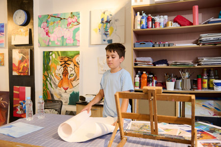 Confident portrait of a Caucasian teenage boy learning painting and drawing in art class, standing at desk against a wall with peintures. Museum. Exhibition gallery. Education. Fine visual art conceptの写真素材