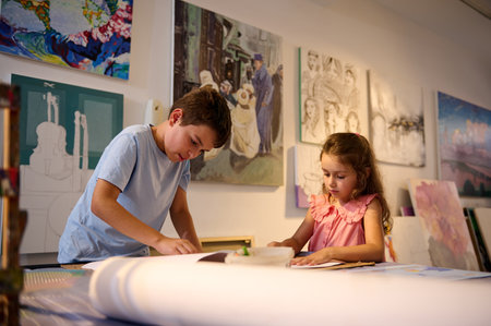 Two Caucasian adorable diverse kids learning painting and drawing at fine art class. Development of...