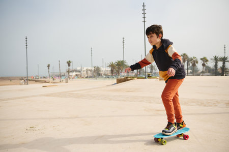 Happy active teenage boy riding on skateboard on an urban skatepark playground, dressed in stylish sportswear. Extreme sport, Happy carefree childhood. Active healthy lifestyle conceptの写真素材