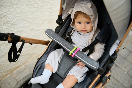 Directly above Authentic portrait of cute baby boy 6-11 months old, sitting in baby pram outdoors,...