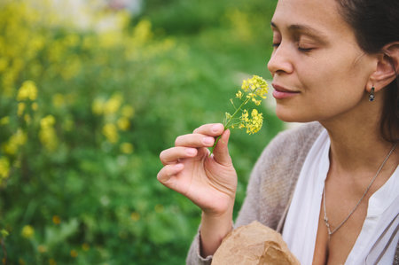 Close-up woman botanist herbalist sniffing flower while collecting medicinal herbs in the mountains...