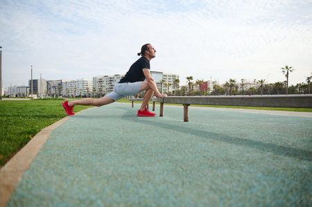 Full length portrait male athlete exercising with crossbar on the urban sportsground. Determined...