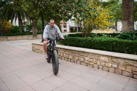 Full length portrait of a handsome Caucasian man commuter renting electric bike, riding in the city....