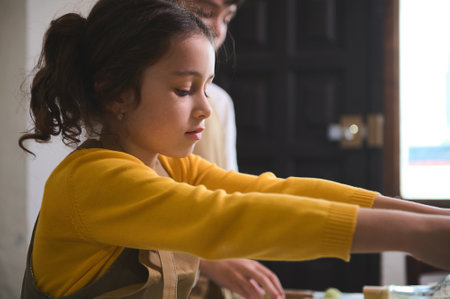 Close-up portrait of a Caucasian little chef girl preparing dumplings during cooking master class...