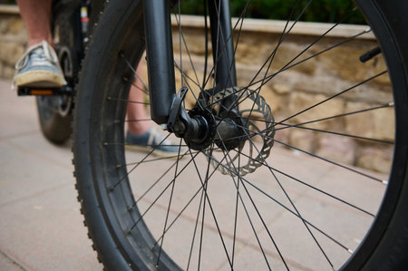 Cropped view of a man cycling in the nature. Details on electric bike bicycle wheel with spokes....