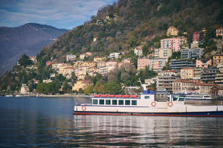 Beautiful touristic boat floating on a clean transparent water of the lake of Como in Italy, against beautiful alpine mountains background. Travel destinations. Tourism. Trip. Famous places conceptの写真素材