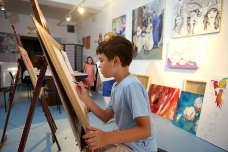 Kids have art class, drawing, painting with teacher in workshop. Engaged children express creativity and learn about art.の写真素材