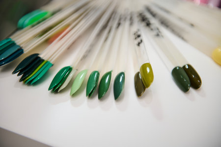 Close-up of assorted nail polish color samples at a beauty salon, showcasing various shades of green arranged neatly.の写真素材
