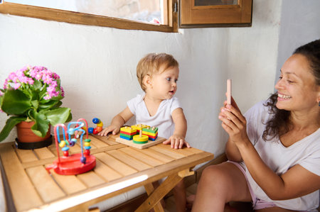 A loving mother and her baby enjoy quality time together at home, playing with colorful toys and...