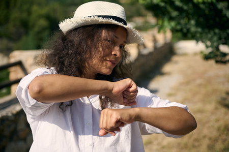 Woman wearing a stylish hat and white shirt, striking a playful pose while enjoying a beautiful...