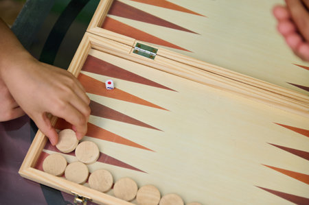 Close-up image of two players engaged in a backgammon game, focusing on the wooden pieces and dice....