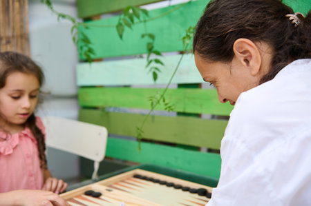 A mother and daughter engaging in a fun game of backgammon while spending quality time together in a...