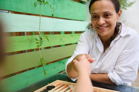 Happy mother and child playing a board game together, sharing a moment of bonding and joy in an...