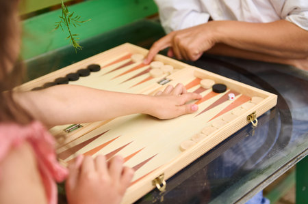 Close-up of two people playing backgammon on a wooden board. The image captures the engaging moment...