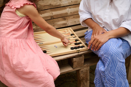 A child and adult enjoying a game of backgammon together outdoors, highlighting family bonding and...