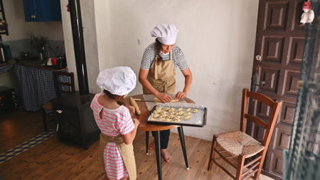 Mother and daughter spending quality time baking together in a cozy kitchen, forming pastry dough...
