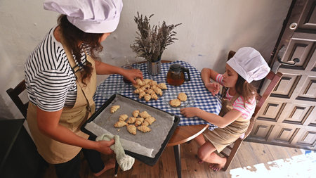 A mother and daughter spend quality time baking croissants together in a cozy kitchen. The little...