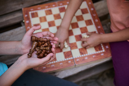 A close-up of two children engaging in a chess game outside, showcasing strategic thinking and...
