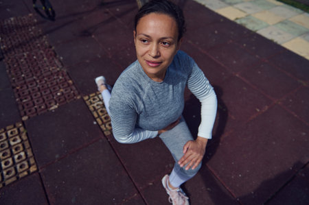 Woman in athletic wear stretching outdoors on a sunny day, emphasizing fitness and well-being in an...